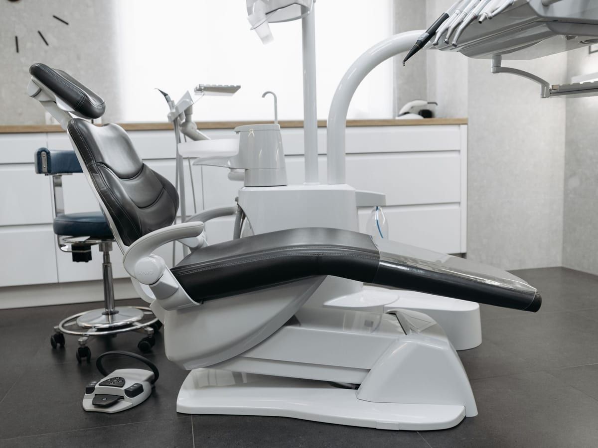 A dental chair with a stool and a foot control